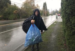 Richard Dick carries cans to cash in at a bottle depot, money he hopes will pay for his ferry ticket to the mainland. (Eric Plummer photo)