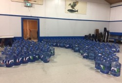 More than 700 donated jugs of water wait for community distribution in the Thunderbird Hall. (Max Thomas photo)