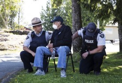 Constable Yannick Harry (left) and sergeant Steve Mancini take a knee beside elder Richard Mundy in a display of solidarity during a peaceful protest in honour of Chantel Moore and George Floyd, in Ucluelet.