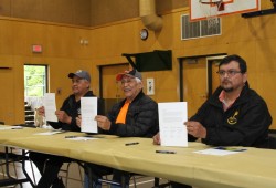 Jeff Jones (far left), Robert Dennis Sr. and Brian Tate, chief councillors of the Pacheedaht, Huu-ay-aht and Ditidaht First Nations, hold the Hišuk ma c̕awak Declaration after signing it at Nitinaht Lake in June 2021. (Eric Plummer photo)