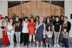 Joshua Watts, back row, second from left, with his family in front of the longhouse he made for his exhibition at the Victoria Arts Council. (Submitted photo)