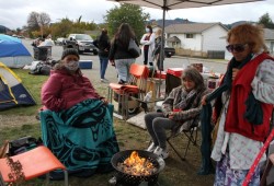 April McCarthy (left), sits with April Nichols as Marian Heiman stands by a fire at the protest encampment.