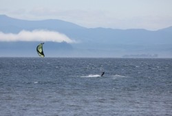 A kite surfer rides the waves before where the Jordan River meets the Juan de Fuca Strait, with Washington State in the distance. Many generations ago people paddled across these waters to settle on southern Vancouver Island to what is now territory of the Pacheedaht First Nation.