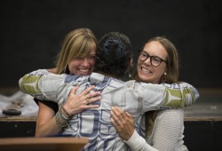 Rebecca Atleo hugs Kate Drexler (left) and Sarah Reid after announcing the new funding for a bighouse in Maaqtusiis Secondary on Flores Island, British Columbia, on August 10, 2022.