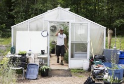 Aaron Woodward walks out of the greenhouse within the Tseshaht community garden in Port Alberni. He tends to the garden year-round and has planted peas, beans, squash and stinging nettle, along with a variety of other fruits and herbs, for the community to pick.