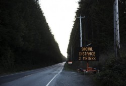 A sign along the highway leading into Tofino reads "Social distance within 2 metres," on Thursday April 9, 2020. 