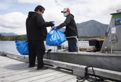 Daniel John (left) hands Tory Atleo Sr. supplies flown in by the non-profit organization, Power To Be, onto the Ahousaht Lone Cone crew boat.