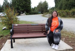 Kae-lynn Johnson sits on a bench bearing a new plaque.