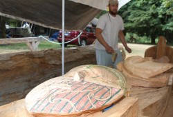 Alan Heta from New Zealand brushes off the pole he is carving with Tim Paul, learning the techniques of the Nuu-chah-nulth art.