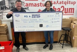 Ucluelet Co-op general manager Mike Bruch, left, hands CBT executive director Rebecca Hurwitz an early Christmas present of $300,000 for a future community teaching kitchen. (Ucluelet Co-op photo)