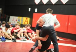 Coach John McDonald demonstrates for the ADSS wrestling team.