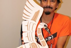 Hipolite Williams of Huu-ay-aht with a swan carving he has for sale.