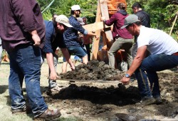 Soil is moved to the base of the totem pole to help stabilize it.