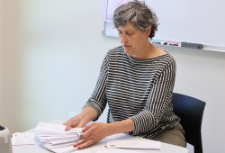 Tourism Tofino’s director of destination stewardship applies stamps to a stack of letters destined for Victoria.