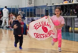 Little Hesquiahts Huukusta and Mediik run with the Descendants banner.