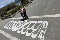 Tla-o-qui-aht children Huumis, Cinkwa and Tsaahtis stand over Tofino’s “reconciliation crosswalk”, which was designed by their dad Hjalmer Wenstob. (Submitted photo)