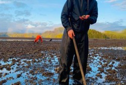 Andrew Clappis of the Huu-ay-aht Youth Warriors pitches in to build a clam garden by removing rocks from the intertidal zone to create space for clams to grow and spawn. (Submitted photo)