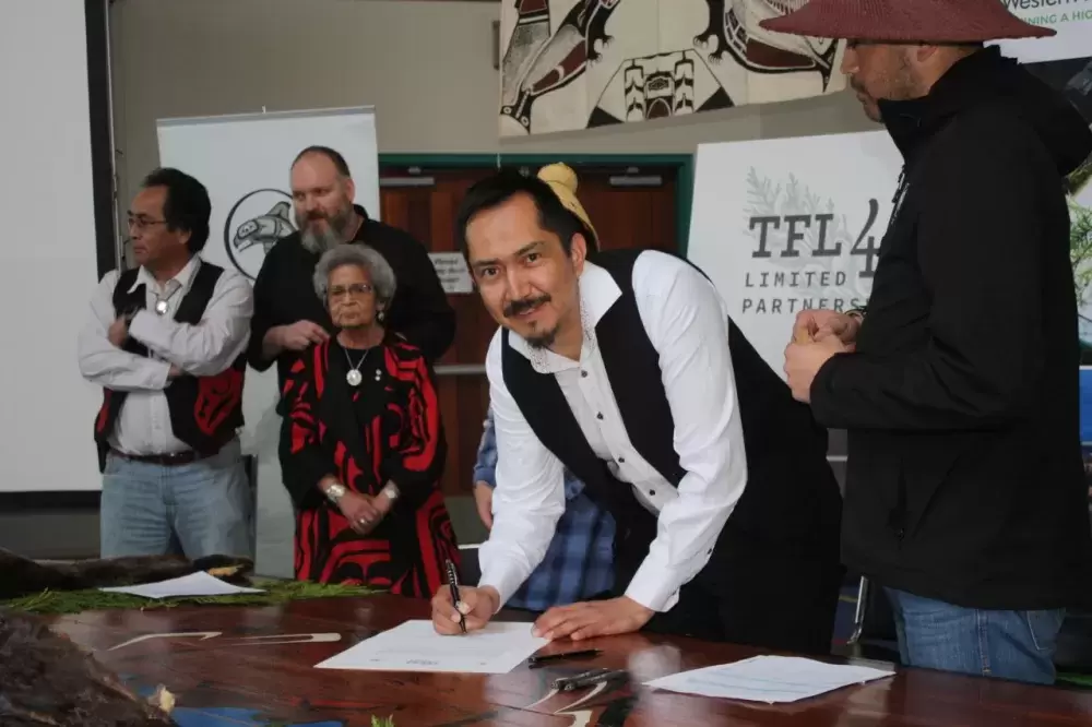 Head Hereditary Chief Derek Peters signs a document during an event in Anacla celebrating a new partnership between the Huu-ay-aht First Nations and Western Forest Products in 2019 (Ha-Shilth-Sa photo)