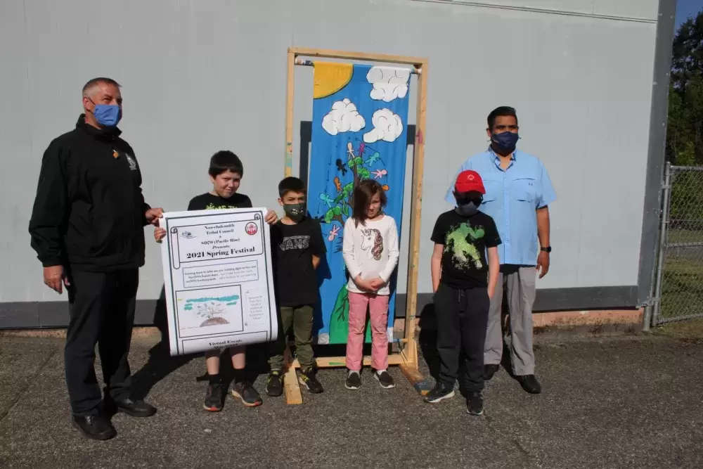 A poster made by Grade 2 and 3 students was selected to promote the 2021 Spring Festival. Pictured are Trey Kyte (left), Liam Horbatch, Sybil Purwins and Macen Avery, with A.W. Neill Principal Darrin Olson and Richard Samuel, a cultural development supervisor with the Nuu-chah-nulth Tribal Council.