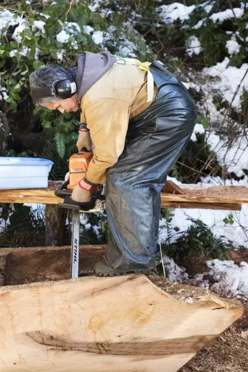 Joe Martin uses a chainsaw to cut through the hull of a dugout canoe, on Feb. 16, 2021. 
