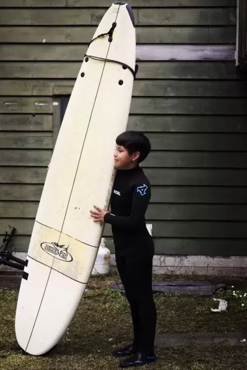 Ali Swan, 9, holds a surf board in Esowista before heading out in the water as part of the youth surf club, near Tofino, on June 14, 2021.