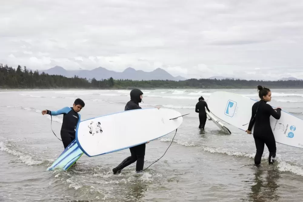 (From left to right) Payton Williams, Hannah Frank, Ali Swan and Cass Frank wade into the ocean in front of Esowista for surf club, near Tofino, on June 14, 2021.