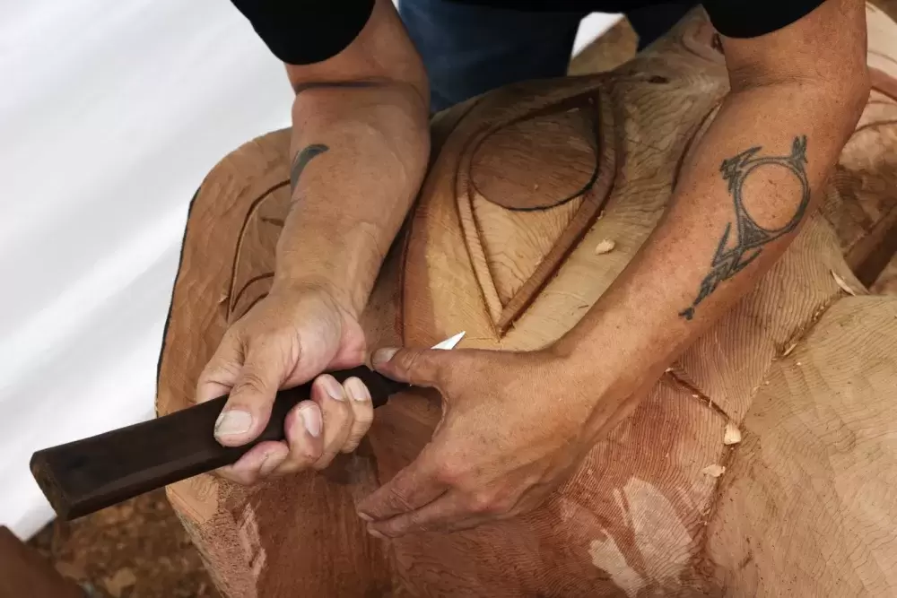 Patrick Amos helps to carve a totem pole at the Tofino Botanical Gardens, on July 9, 2021.
