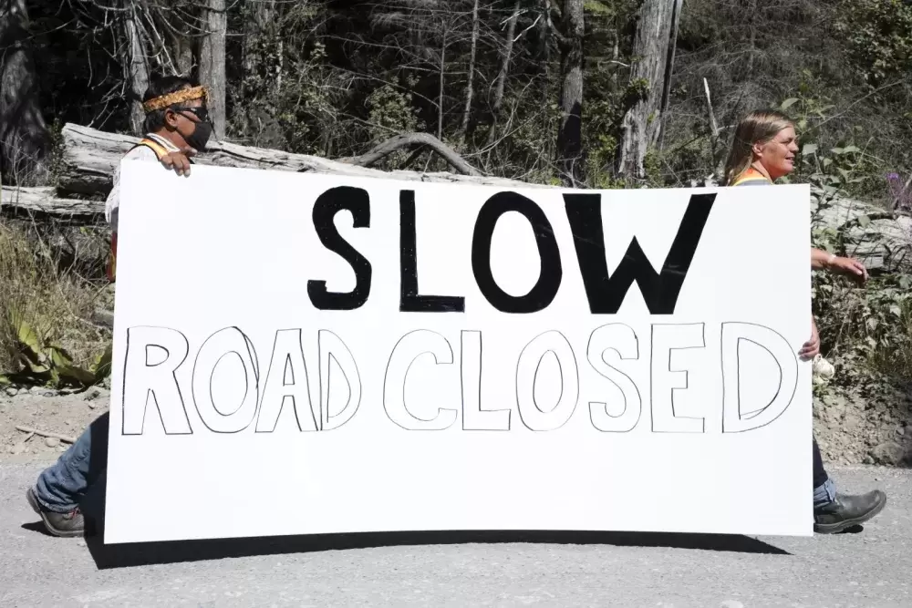 Trent and Jessie Masso carry a road closure sign down West Main Forest Service Road, near Tofino, on August 10, 2021. 