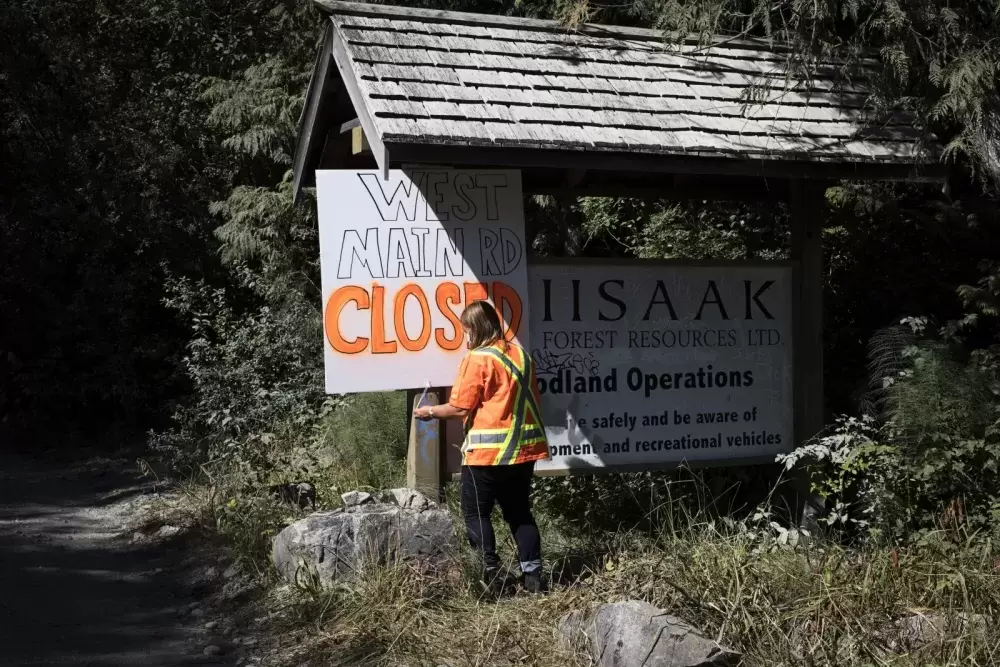 Jessie Masso hangs a road closure sign at the entrance of West Main Forest Service Road, near Tofino, on August 10, 2021. 