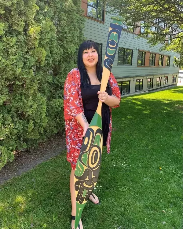 Williams holds a thunderbird paddle carved from yellow cedar.