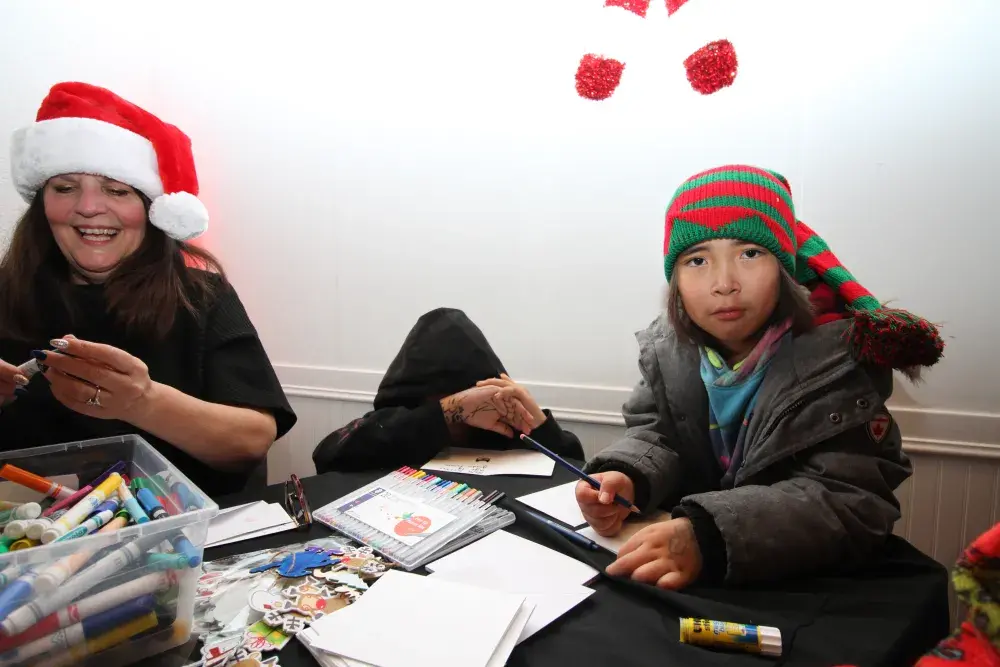 Mia Thomas-Watts (right) works on a Christmas card as Raven Touchie covers her face from the camera, next to Kenna Smith, a mother support worker with the Nuu-chah-nulth Tribal Council.