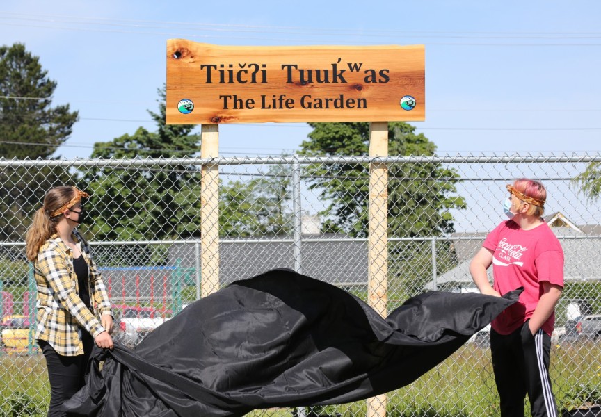 Grade 9 students Gabriella Stanley (left) and Riley Swanson unveil the name for the Eighth Avenue Learning Centre's new garden on June 17.