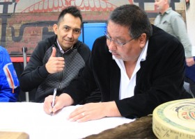 Tyee Ha'wilth Tliishin gives a thumb's up as Ha'wilth Mexis Tom Happynook signs the transfer documents